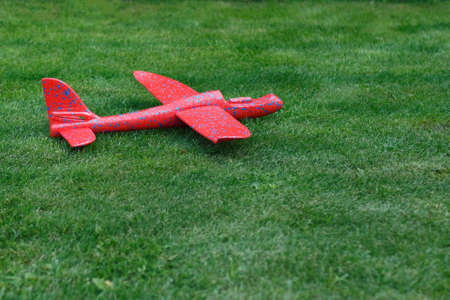 Red toy airplane lies on green grass