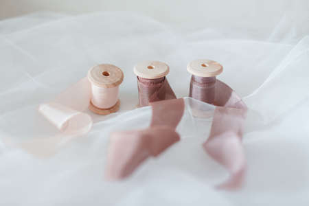 Decorative ribbons of different colors, wound in wooden reels on a fabric backgroundの写真素材