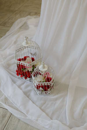 Wedding decorations: white cage with flowers on a fabric backgroundの写真素材