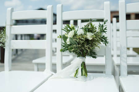 White wedding bouquet of the bride stands on a white chairの写真素材