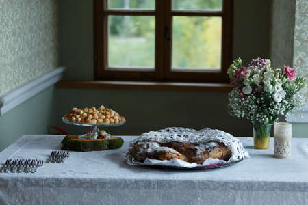 Bread, flowers, forks, a candle on the kitchen table. Window in the backgroundの写真素材