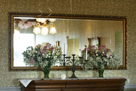 Candlestick with candles and bouquets of flowers in vases standing on the table. In the background is a mirror.の写真素材