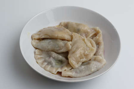 Boiled dumplings with butter in a white plate on a white backgroundの写真素材