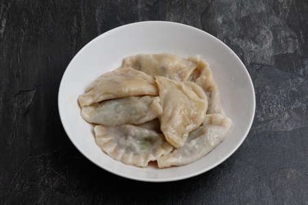 Boiled dumplings with butter in a white plate on a dark backgroundの写真素材