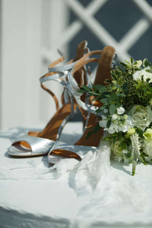 Wedding accessories on a white table: a brideÐ²Ðâ¢s bouquet, shoes and a white ribbonの写真素材