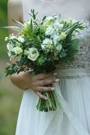 White wedding bouquet in the hands of the bride close-upの写真素材