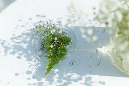 Wedding rings on a fern, decorated with flowers and lie on a glass plateの写真素材