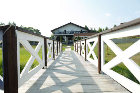 A wooden walkway with a white fence leading from the pier to the house.の写真素材