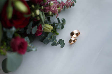 Wedding rings and bridal bouquet on a white backgroundの写真素材