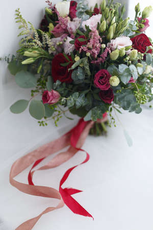 Wedding bridal bouquet of bright roses with pink and red ribbons on a white backgroundの写真素材