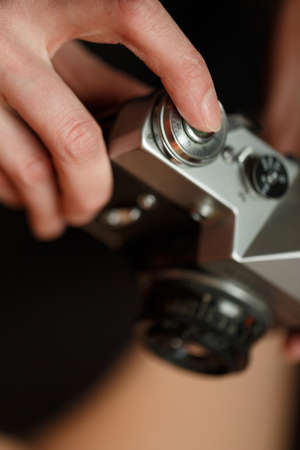 The girl holds a camera in her hands and presses the shutter button. Close-up.の写真素材