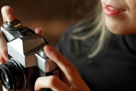 The girl holds a camera in her hands and presses the shutter button. Close-up.の写真素材
