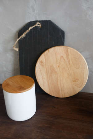 Black and yellow kitchen boards stand on a shelf against the wall, next to a container for cereals....