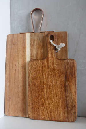 Two wooden kitchen boards stand on a shelf against the wall. Close-upの写真素材