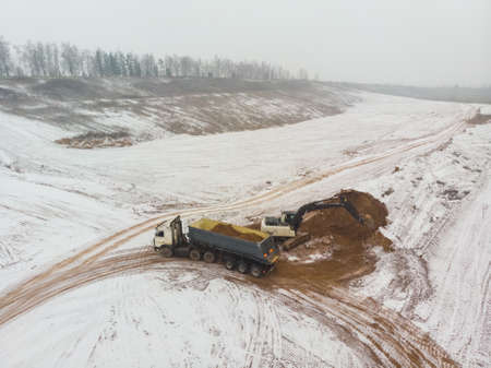 An excavator loads a truck with earth. View from above. Aerial photographyの写真素材
