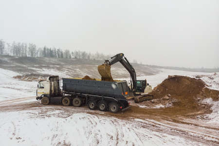An excavator loads a truck with earth. View from above. Aerial photographyの写真素材