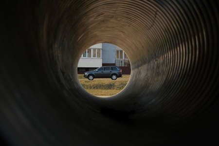 Passenger car standing near the house. View through the pipeの写真素材
