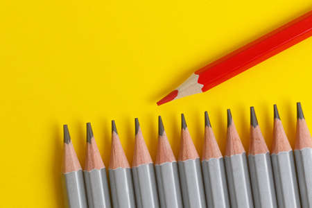 red pencil and gray pencils on a yellow paper background. Leader concept, different, uniqueの写真素材