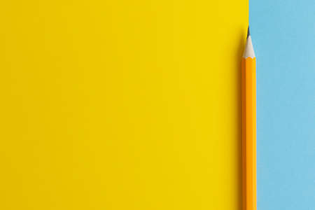 An interactive photo composition of an orange pencil and space for creative thinking (text) is used for presentation in the field of education, business or creativity. Lighting on a pencil in the studio. Blue and yellow backgroundの写真素材