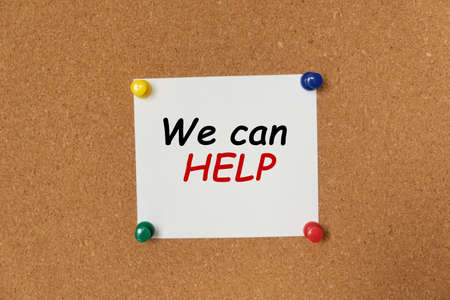 Text We can HELP written on a sticker pinned on a cork boardの写真素材