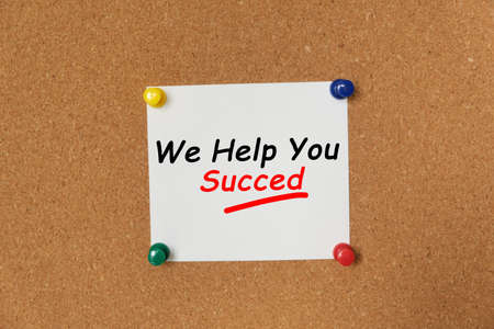 Text We Help You Succed written on a sticker pinned on a cork boardの写真素材