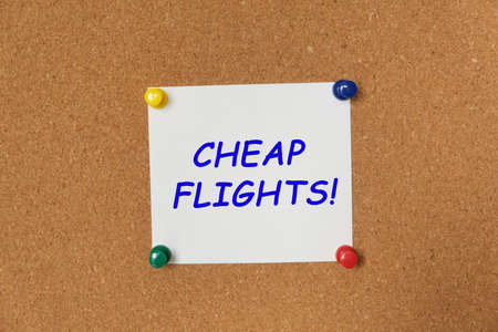 Text CHEAP FLIGHTS written on a sticker pinned on a cork board