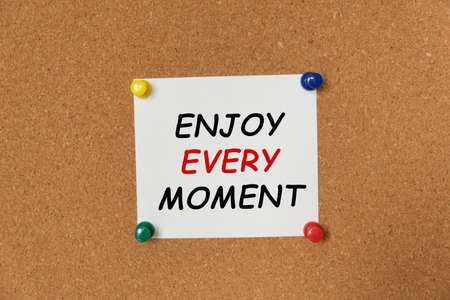 Text ENJOY EVERY MOMENT written on a sticker pinned on a cork boardの写真素材