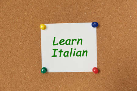 Text Learn Italian written on a sticker pinned on a cork boardの写真素材