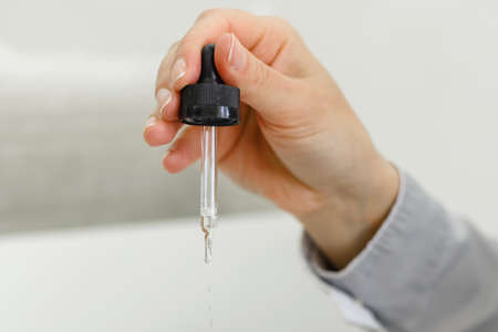 The doctor picks up the medicine with a dropper from a bottle. Close-up