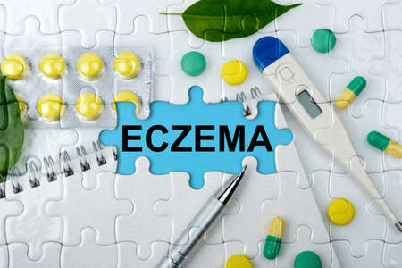 Double exposure. Puzzles with the image of tablets, a notebook, a thermometer and a pen with the inscription -ECZEMA. The concept of medicine.の写真素材
