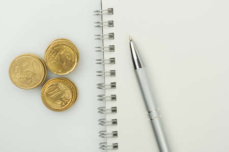 Coins, blank notepad and pen on a white background. Business and technology concept.の写真素材