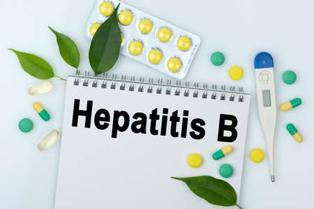 On the table are pills, a thermometer, leaves and a notebook with the inscription -Hepatitis B. The concept of medicine.の写真素材
