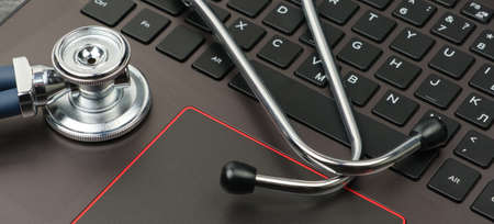 Silver stethoscope on a modern laptop keyboard. Medical conceptの写真素材