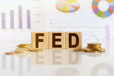 Federal Reserve. FED the word on wooden cubes, cubes stand on a reflective surface, in the background is a business diagram. Business and finance conceptの写真素材