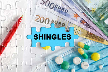 Double exposure. Puzzles with the image of pills, medical mask, pens and euro with the inscription -SHINGLES. The concept of medicine.の写真素材
