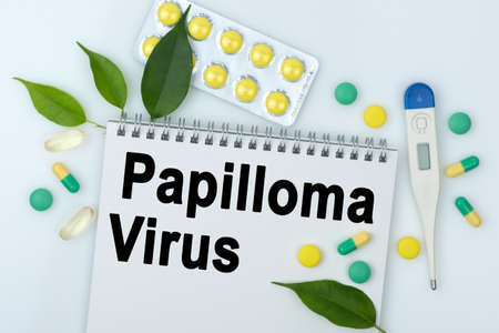On the table are pills, a thermometer, leaves and a notebook with the inscription -Papilloma Virus. The concept of medicine.の写真素材