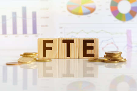 Full Time Equivalent. FTE the word on wooden cubes, cubes stand on a reflective surface, in the background is a business diagram. Business and finance conceptの写真素材