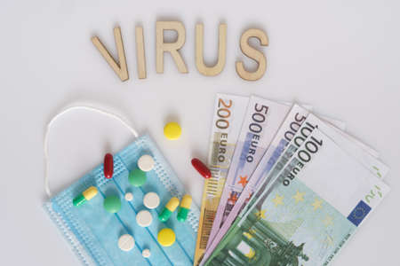 The inscription Virus , dollars, medical mask, surrounded by drugs and pills. The concept of medicine. Shot from above on a white background.の写真素材