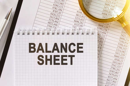 On the table are financial reports, a pen, a magnifying glass and a notebook with the inscription - BALANCE SHEET. Business and finance concept.の写真素材
