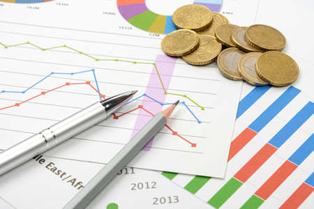 Business goal concept. Business accessory, graph charts and pencil and coins on the table.の写真素材