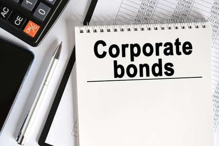 On the table lies a smartphone, a calculator and a notebook with the inscription - Corporate bonds. Business conceptの写真素材