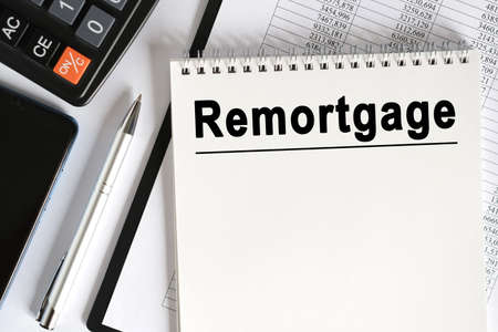 On the table lies a smartphone, a calculator and a notebook with the inscription- remortgage. Business conceptの写真素材