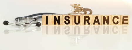 INSURANCE the word on wooden cubes, cubes stand on a reflective white surface, on cubes - a stethoscope. Medicine conceptの写真素材