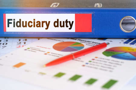 On the table are pie charts, a pen and a folder with the inscription - Fiduciary duty. Business and finance concept.の写真素材