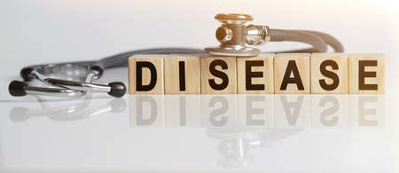 DISEASE the word on wooden cubes, cubes stand on a reflective white surface, on cubes - a stethoscope. Medicine conceptの写真素材