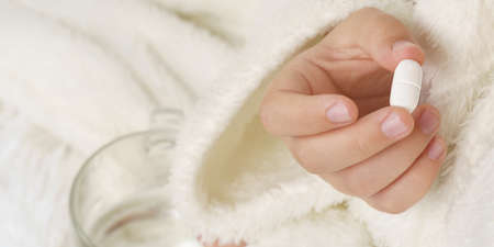 A girl takes a thermometer from the table where the medicines are. Medical concept.の写真素材