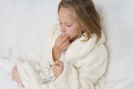 A girl takes a thermometer from the table where the medicines are. Medical concept.の写真素材