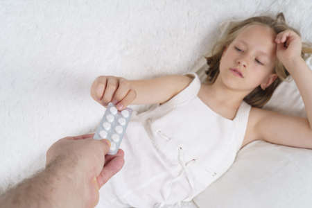 A man gives medicine to a sick teenage girl. Girl out of focus. Medical concept.の写真素材