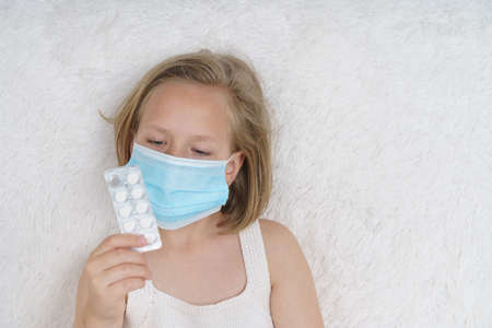 Sick teenage girl is looking through the packaging with pills. Medical concept.の写真素材