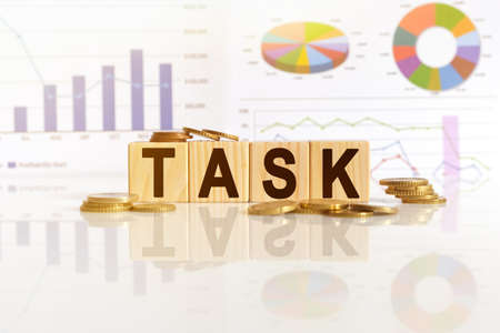 TASK the word on wooden cubes, cubes stand on a reflective surface, in the background is a business diagram. Business and finance conceptの写真素材